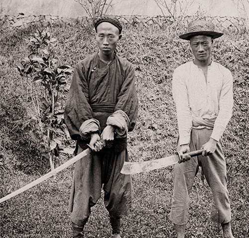 图为清朝末期的刽子手在展示大砍刀,看着这明晃晃的砍刀,再看看他们的