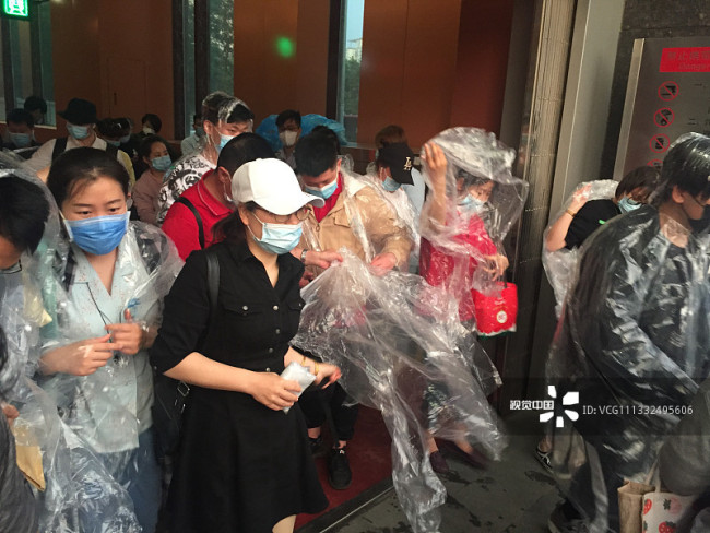 北京晚高峰突降暴雨 地铁站免费为乘客发放雨衣