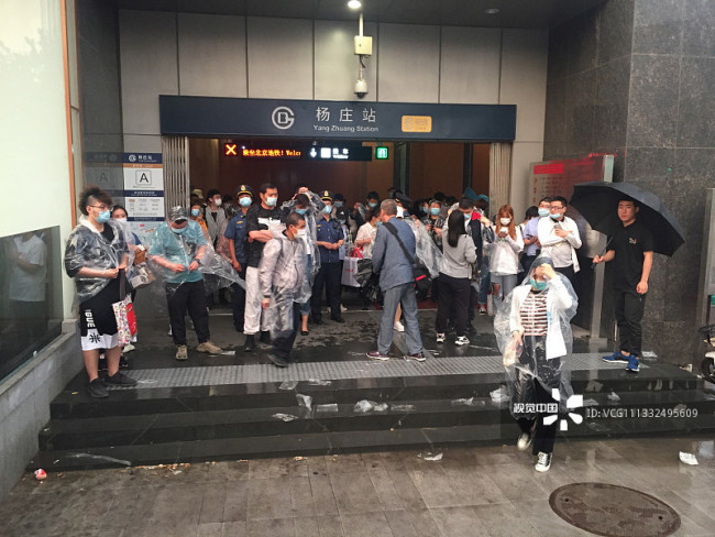 北京晚高峰突降暴雨 地铁站免费为乘客发放雨衣